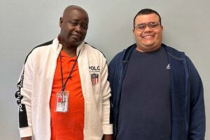 Community Job Coach Prince Metzger poses for a photo with an Eden participant before taking them to work.