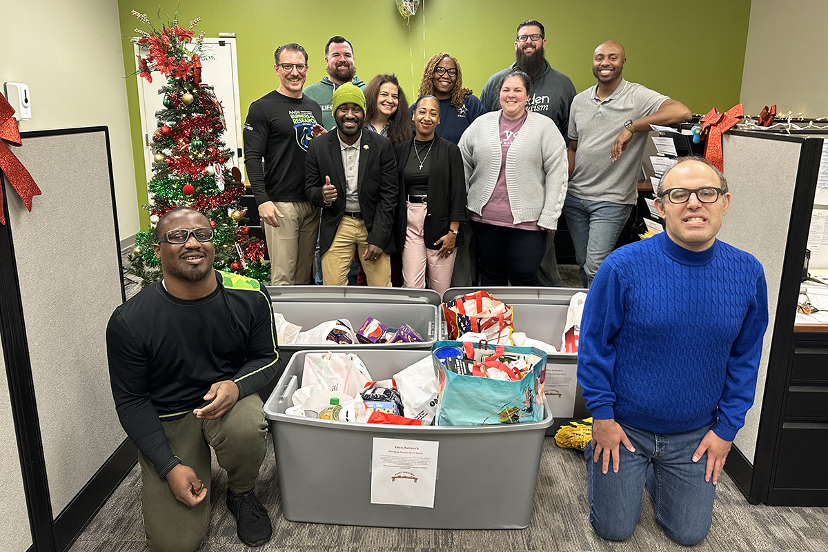 Eden staff and participants smile around the three bins of donated food!