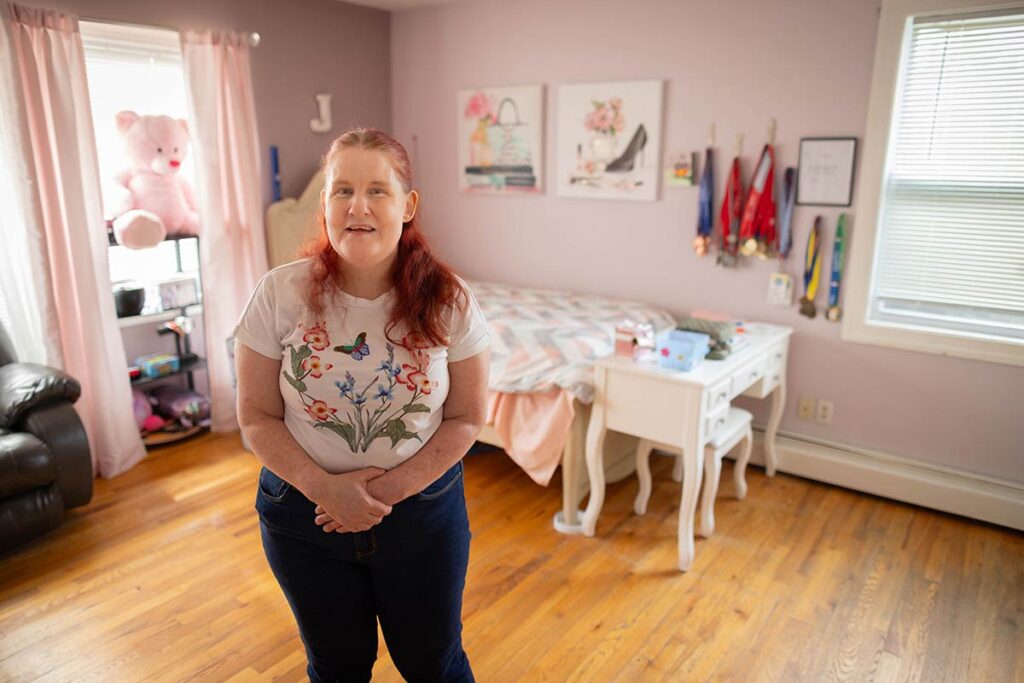 Joelle smiles while standing in her bedroom