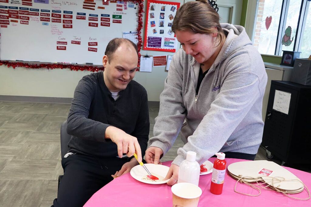 Amanda Popp helping a participant with an arts and crafts project.