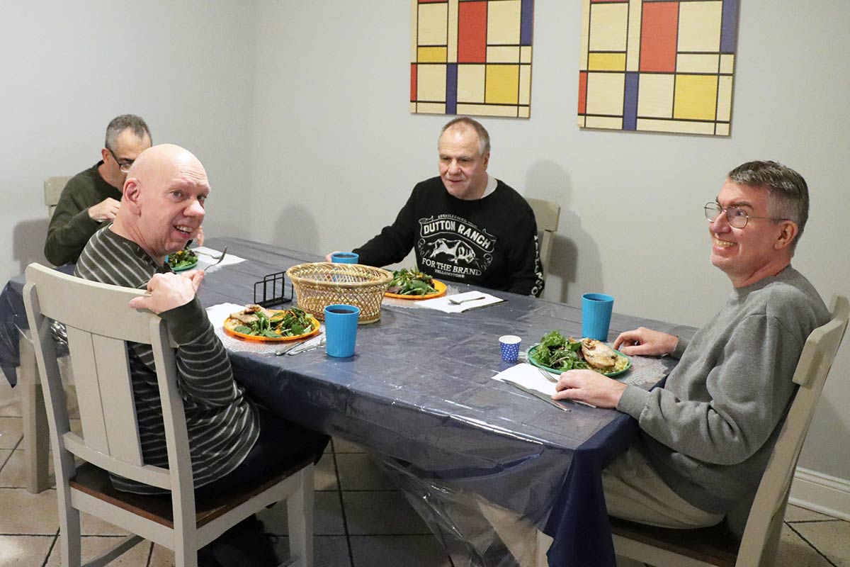 Four men gathered around a dinner table, smiling