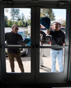 Two men clean a glass door