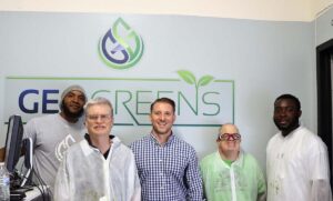 Five men smile for a photo in front of a sign that reads "GeoGreens"